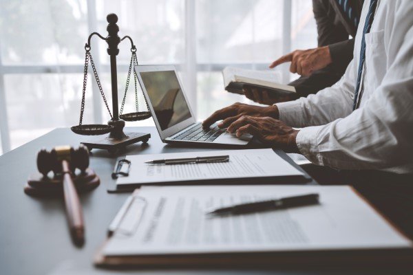 Abogados especialistas en seguros de vida trabajando en laptop junto a una balanza, documentos y mazo legal