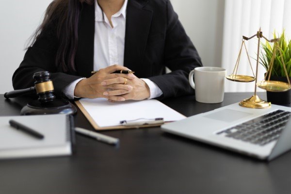 Abogada sentada en su escritorio frente a laptop, mazo y balanza, propio de abogados especialistas en seguros de vida.