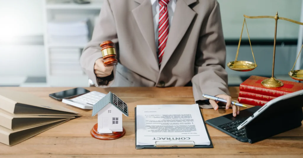 Especialista en servicios jurídicos inmobiliario representados con mazo de madera y maqueta de casa en oficina de leyes.