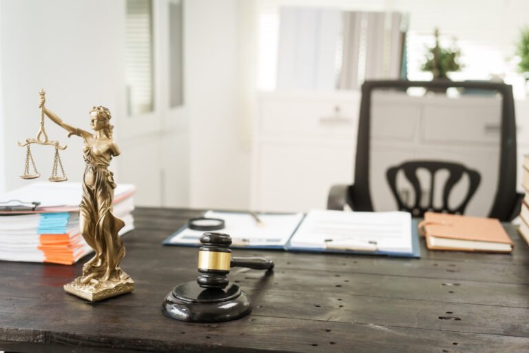 Escritorio con mazo, expedientes y estatua de justicia ejemplifica qué hacer si mi seguro no me quiere pagar.