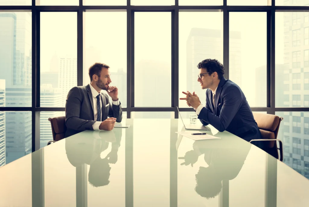 Imagen de un abogado de empresa sentado con un colaborador interactuando sobre cómo tomar decisiones para no ser abusado por sus cocios en conflicto