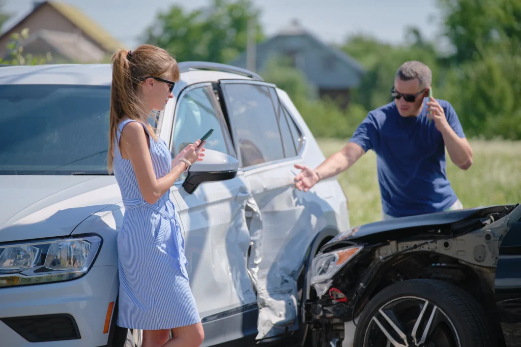 Seguro de daños a terceros en accidente de tránsito: Fotografía de dos personas que tuvieron un percance en auto y ahora deben esperar al perito