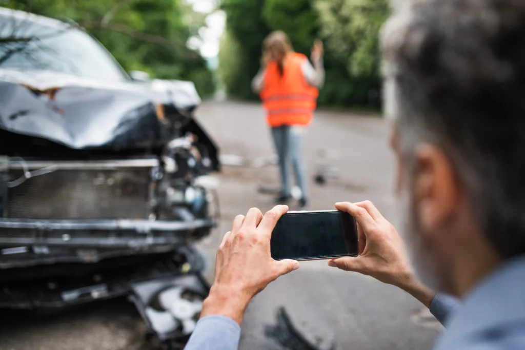 Seguro de daños a terceros en accidente de tránsito: Imagen de un hombre tomando fotografías de evidencia por si quieren culparlo a el de haber provocado el choque